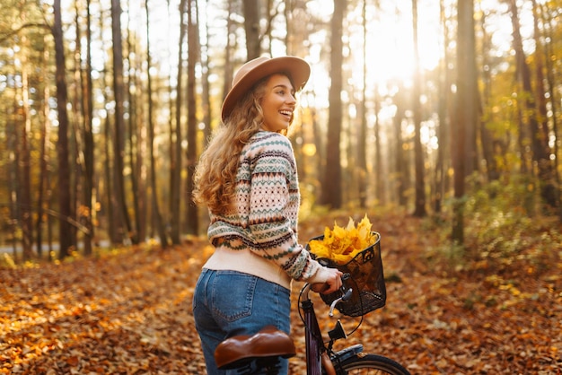 Happy woman with curly hair rides bicycle in sunny autumn park Outdoor Lifestyle Nature concept