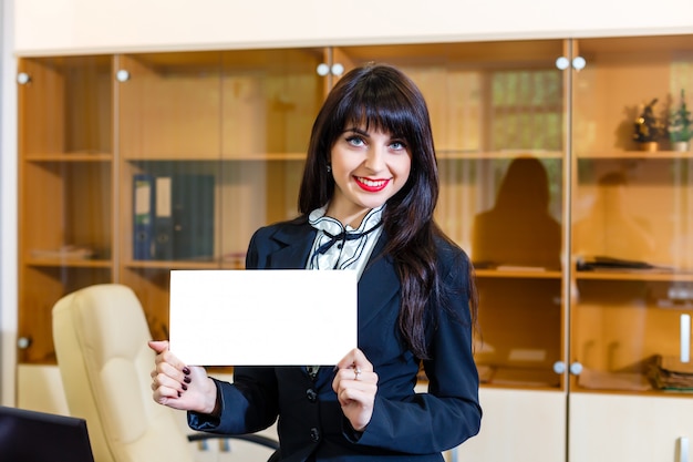 Happy woman with empty card in office