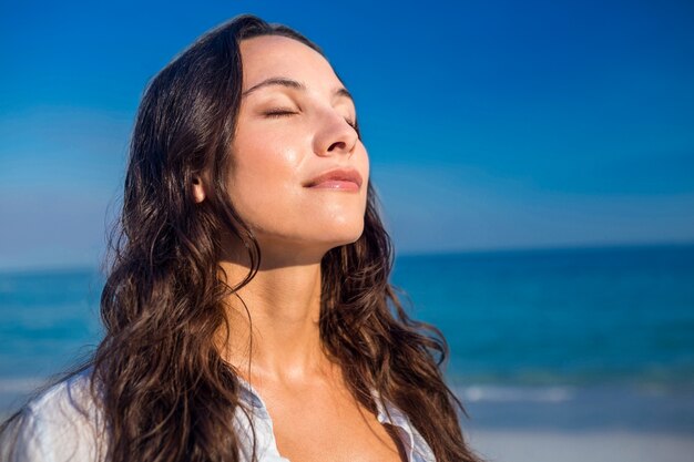 Happy woman with eyes closed at the beach