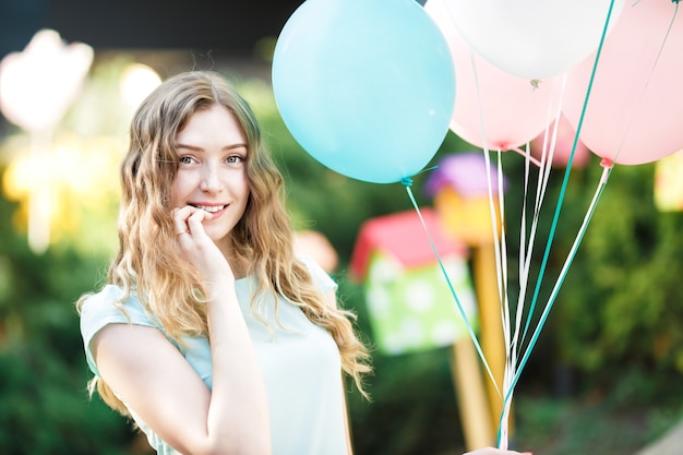 Happy woman with flying multicolored balloons in the city