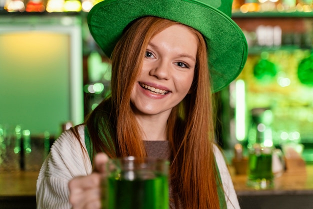 写真 聖を祝う帽子と幸せな女性。ドリンクを飲みながらバーでパトリックの日