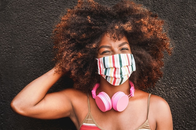 Happy woman with headphones wearing face mask during coronavirus outbreak