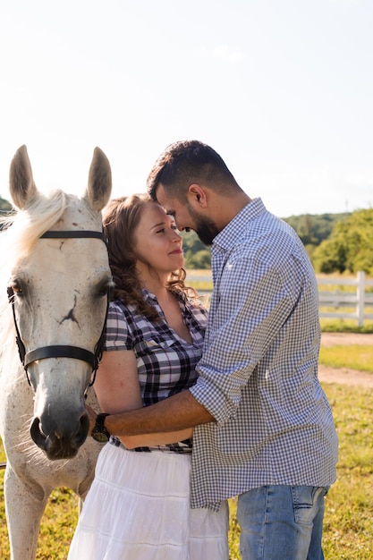 The happy woman with her sweetheart stand next to a horse