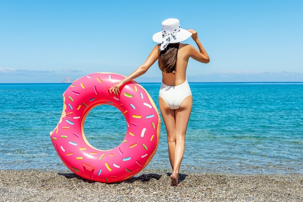 Donna felice con la ciambella gonfiabile sulla spiaggia tropicale