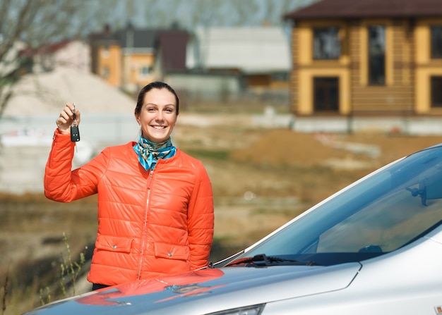 Donna felice con le chiavi in mano sopra l'auto a casa