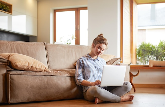 Happy woman with laptop on living room floor