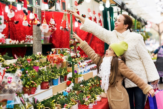 Donna felice con la piccola figlia che compra composizione floreale