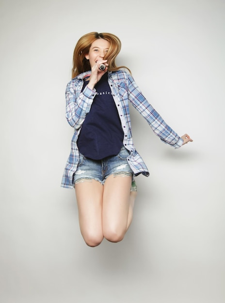 Photo happy woman with microphone jumping and singing