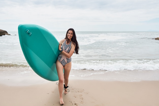 Donna felice con paddle board sulla spiaggia