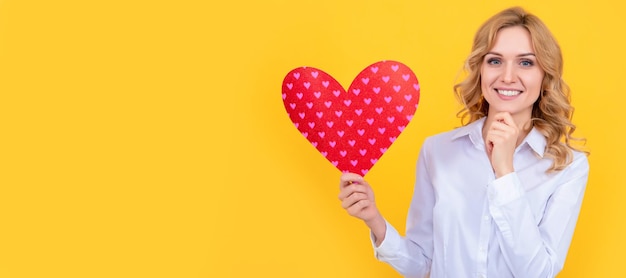 Happy woman with red love heart on yellow background february 14 Woman isolated face portrait banner with mock up copy space