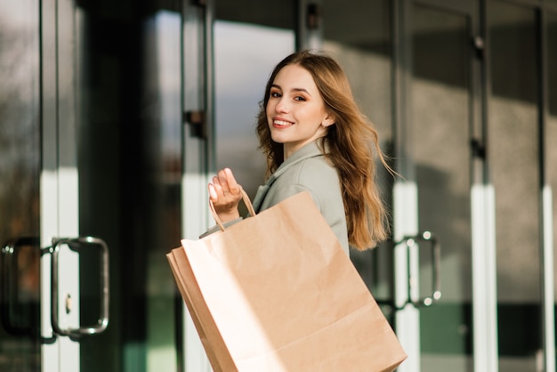 ショッピングを楽しんで買い物袋を持つ幸せな女性。消費主義、ライフスタイルの概念
