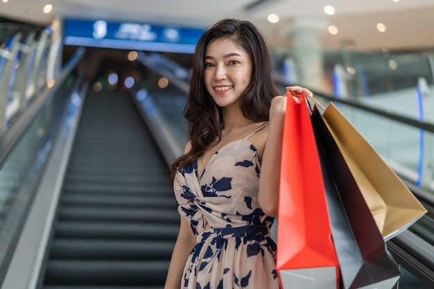 Happy woman with shopping bags on escalator in mall