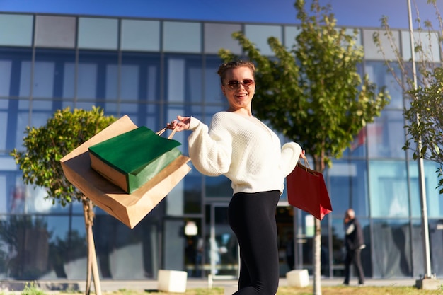 Happy woman with shopping bags walking in city from mall excited girl enjoys purchases on black