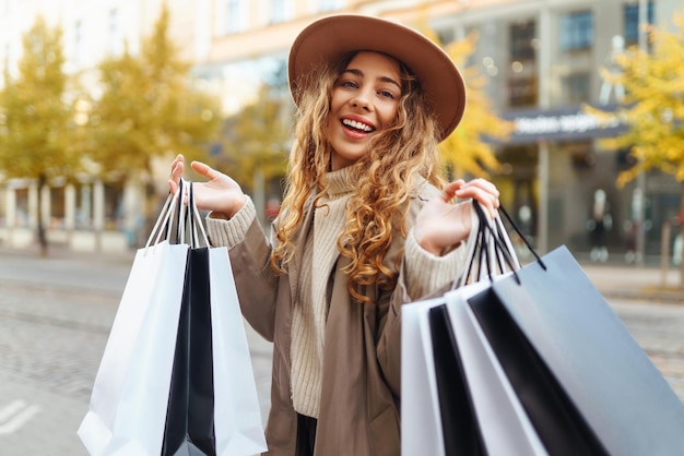 Donna felice con le borse della spesa che cammina per strada acquisti sconti black friday concetto di vendita