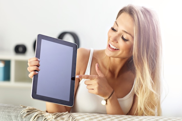 happy woman with tablet on sofa