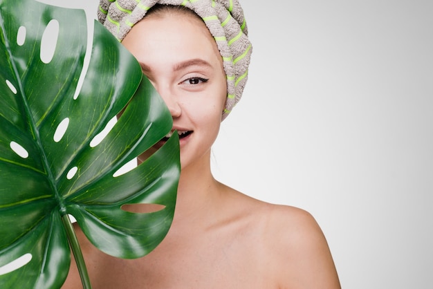 Happy woman with a towel on her head holds a large leaf