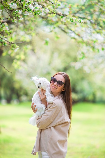 Happy woman with a white dog in nature. Girl playing with a puppy in the park