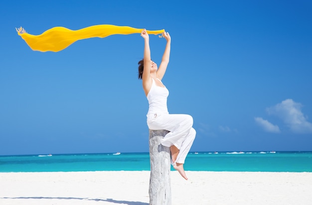 happy woman with yellow sarong on the beach