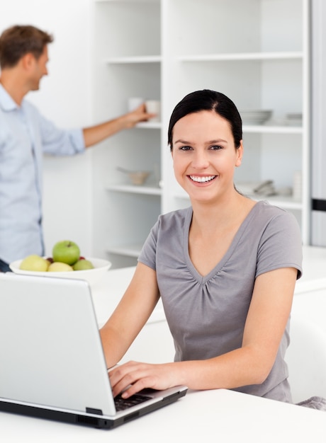 Happy woman working on the laptop in the kitchen with her boyfriend