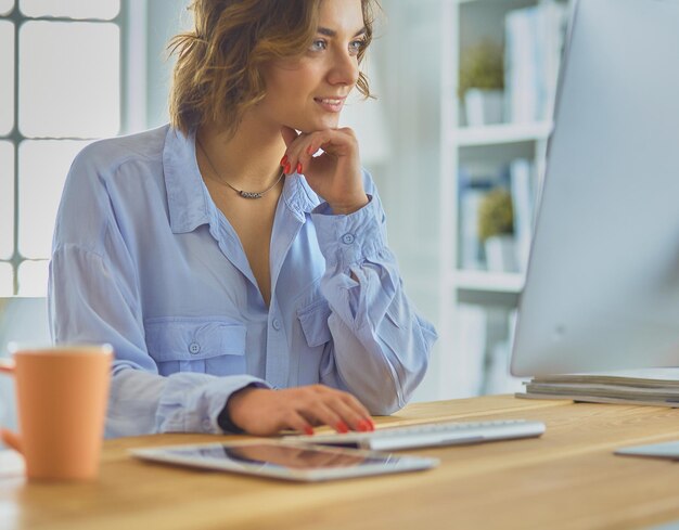 Happy woman working using multiple devices on a desk at home
