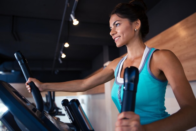 Happy woman workout on exercises machine in fitness gym