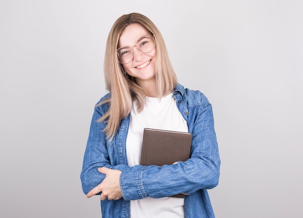 Happy woman writer with blond hair, glasses and a denim shirt holds a written book in her hands and smiles. international writers day