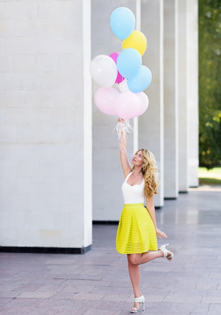 Happy woman in yellow dress with colorful balloons