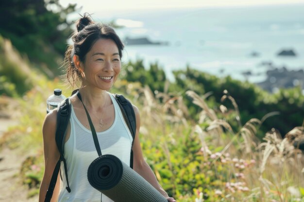 Photo happy woman in yoga outfit walking with mat and water bottle at the park by sea