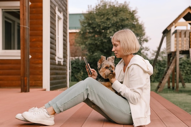 幸せな女性とヨークシャーテリア犬がスマートフォンで自分撮りの肖像画を楽しんでいます