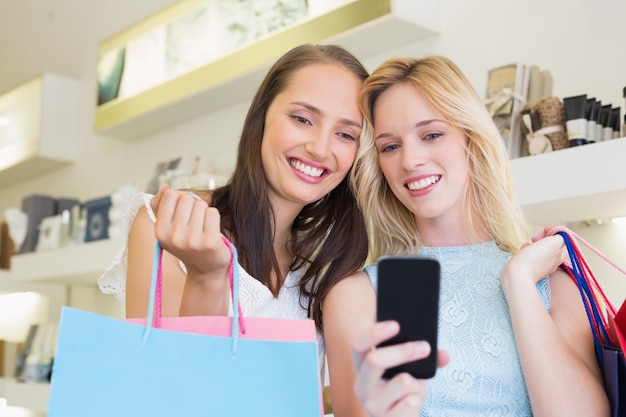 Happy women friends looking at smartphone