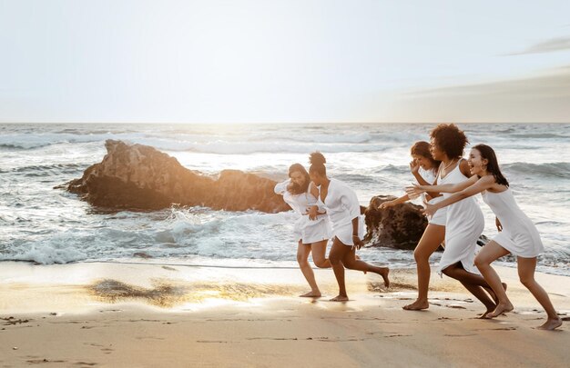 Happy women running along ocean shore while celebrating bachelorette party on the beach full length