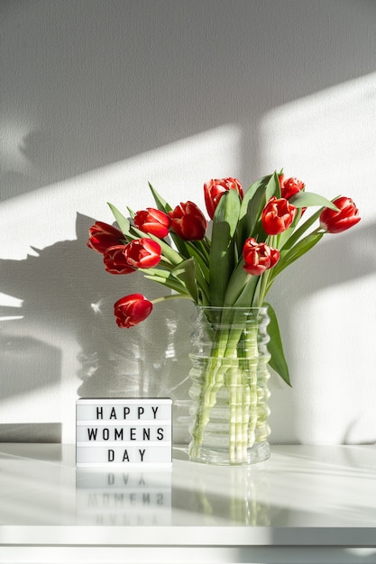 幸せな女性の日。リビングルームのドレッサーに赤いチューリップの花束。