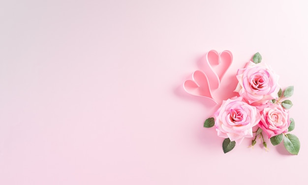 幸せな女性の日のコンセプト。ピンクのパステル背景にハートとバラの花の平面図です。