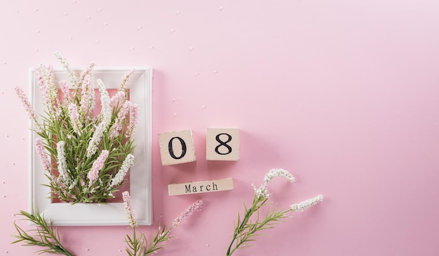 Happy Women's Day decoratie concept gemaakt van bloem papier hart en houten kalender op roze pastel achtergrond