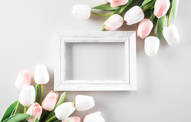 Concetto di decorazione per la festa della donna felice, bellissimi tulipani e cornice per foto su sfondo pastello.