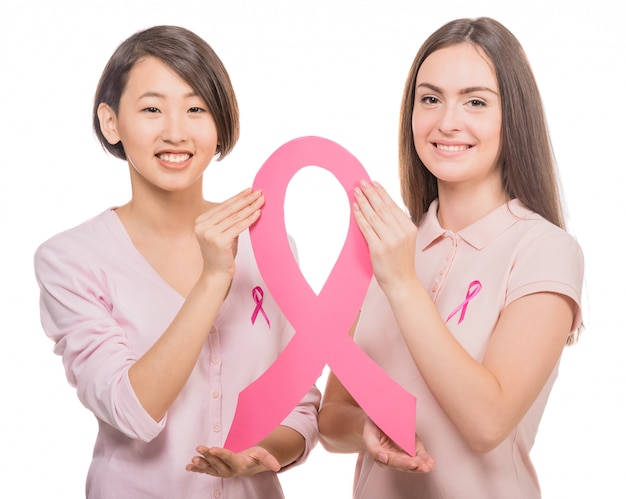 Happy women wearing pink tops and ribbons for breast cancer.