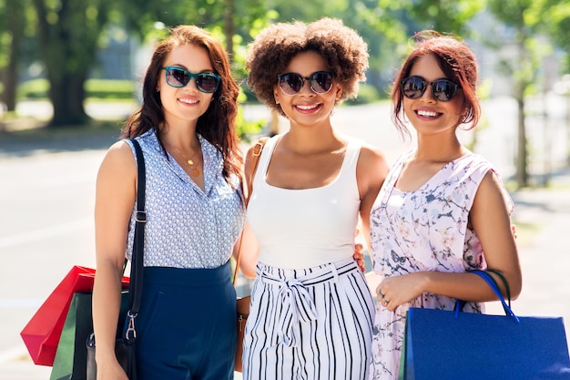 happy women with shopping bags in city