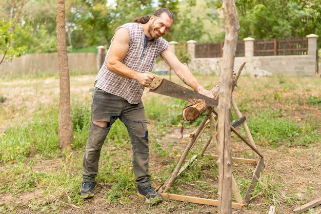 Happy woodcutter sawing wood in an garden