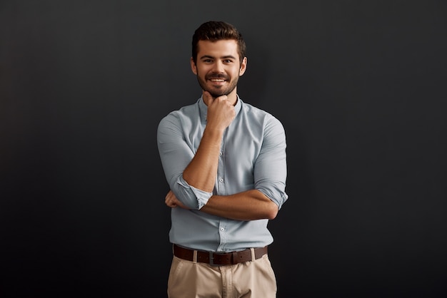 Happy to work here cheerful young bearded man looking at camera with smile and touching