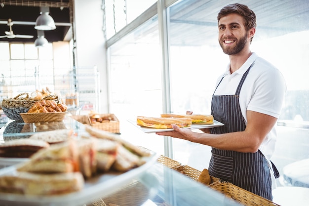 happy worker holding sandwiches