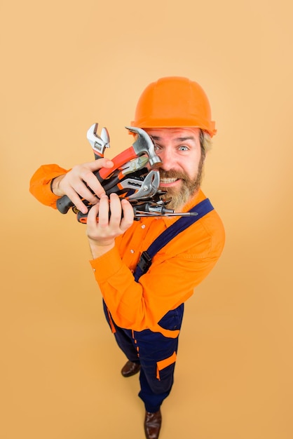 Happy worker holds repair tools building builder in construction helmet repairment tools industrial