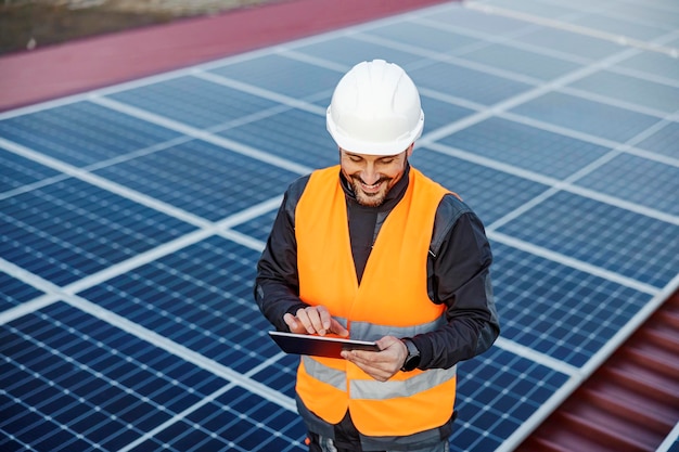 A happy worker testing solar panels with tablet