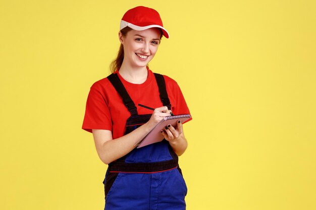 Happy worker woman writing in paper notebook making to do list writes down orders