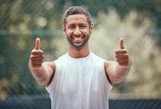 幸せなはいありがとうまたは成功は、テニスコートで笑顔でスポーツマンの親指を立てます