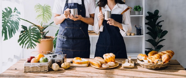 Photo happy young adult couple making breakfast and drinking coffee together in cozy home kitchen in morning at home preparing meal and smiling lifestyle leisure and love concept