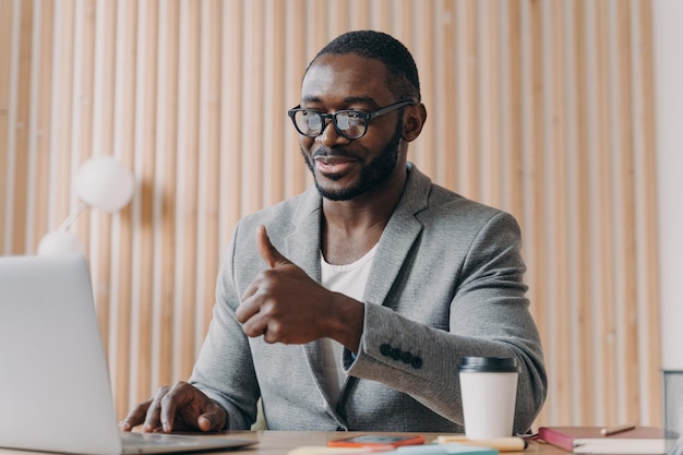 Счастливый молодой афроамериканский бизнесмен разговаривает онлайн на ноутбуке с клиентом или деловым партнером