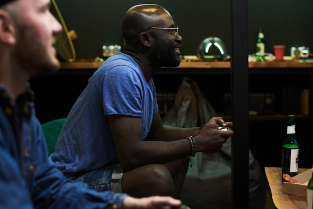 Happy young african american man in blue tshirt playing video game