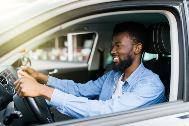 通りの道路で車を運転して幸せな若いアフリカ系アメリカ人の男