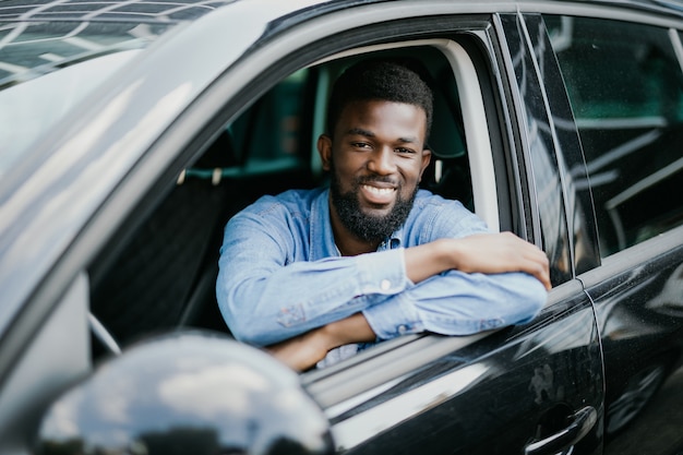 Felice giovane uomo afroamericano alla guida di un'auto