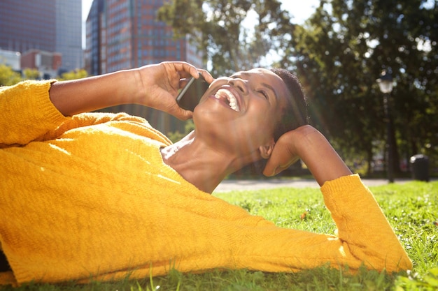 happy young african american woman relaxing in park and talking with cellphone